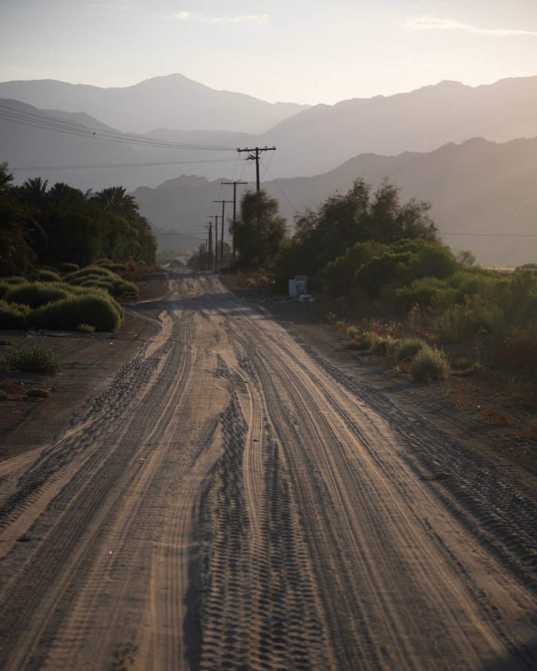 A dirt road leads to mountains surrounded by hazy air.